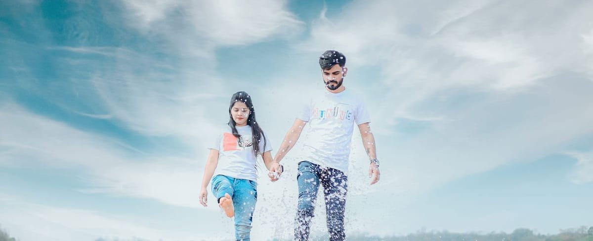 Couple walking through shallow water at golden hour